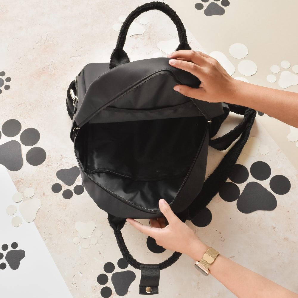 Mains ouvrant le compartiment principal du sac noir