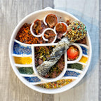 Assiette ronde compartimentée garnie de friandises et poudres colorées