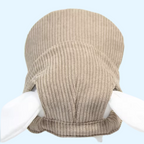 Casquette beige tenue par deux mains, vue de dessus