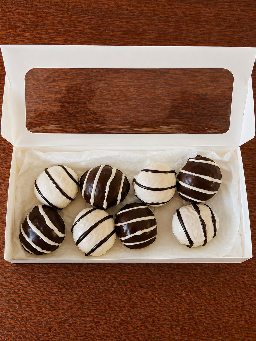 Coffret ouvert de bouchées bicolores sur table en bois