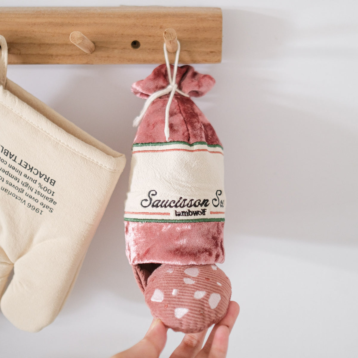 Saucisson suspendu à une patère à côté d'un gant de cuisine