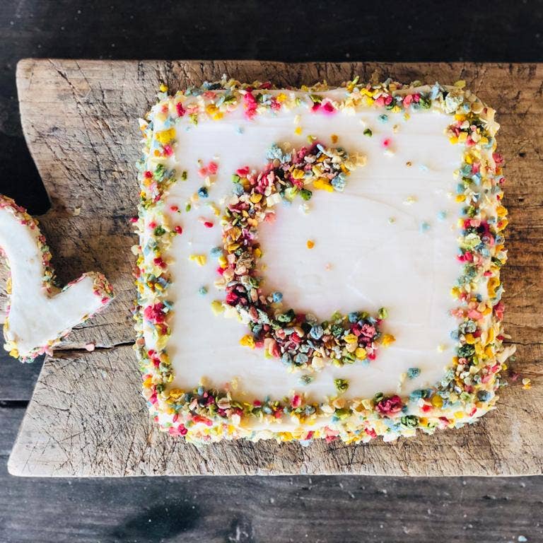 Gâteau glacé blanc décoré de vermicelles colorés sur planche