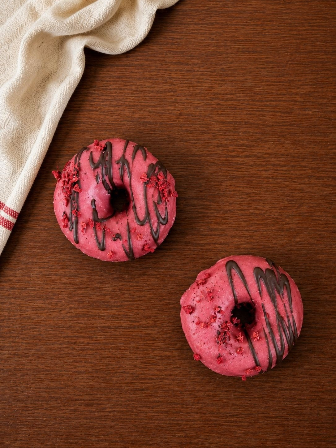 Deux donuts roses posés sur une table en bois
