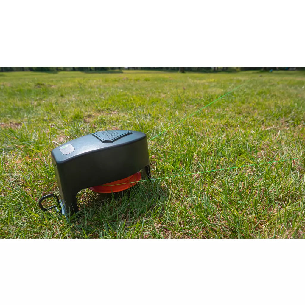 Boîtier moteur noir posé sur la pelouse avec sa ligne
