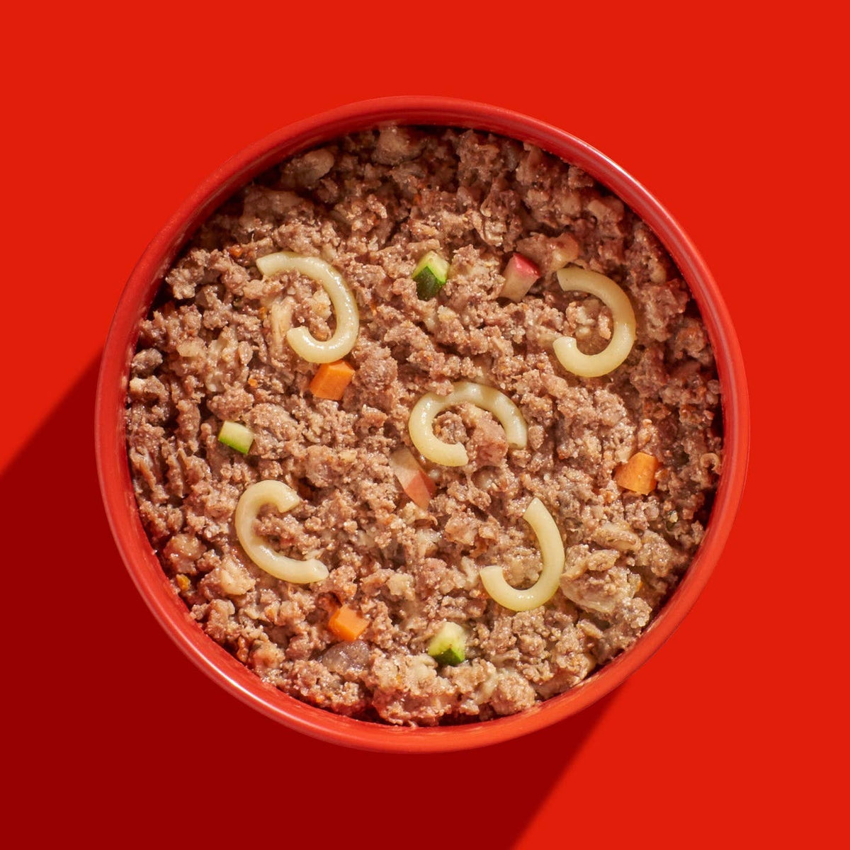 Gamelle rouge remplie de viande et pâtes vue de dessus