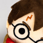 Gros plan du visage de la peluche Harry Potter : cicatrice brodée et lunettes