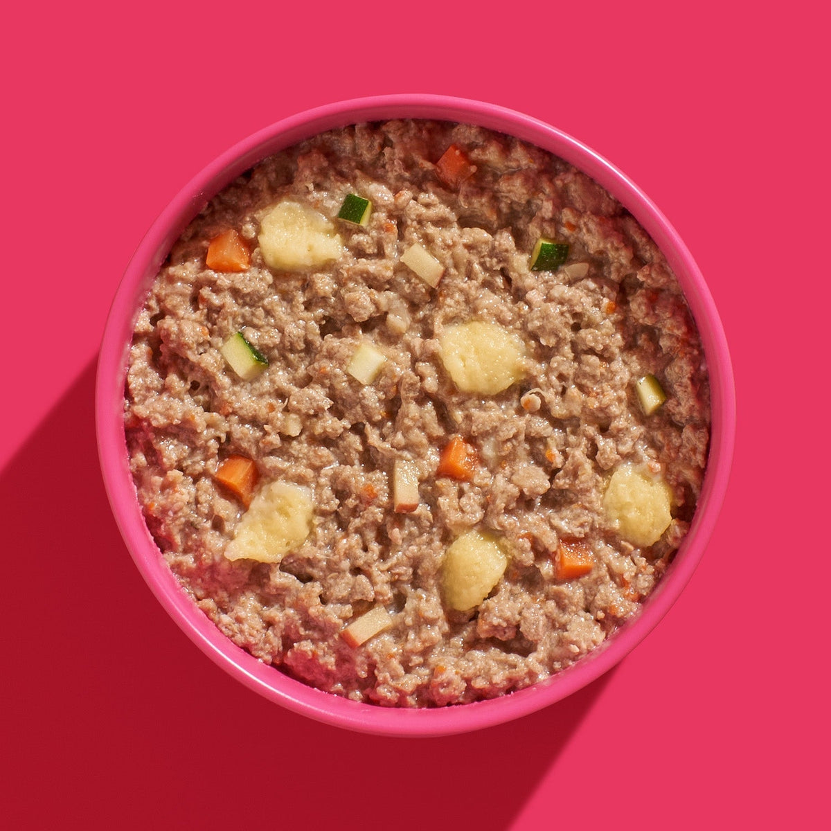 Gamelle rose remplie de viande et légumes vue de dessus