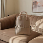 Sac beige posé sur un canapé en cuir