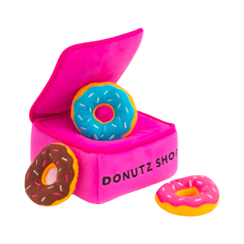 Boîte Donutz Shop rose ouverte et trois donuts à cacher