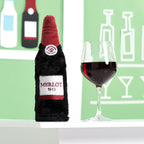 Peluche bouteille de vin rouge ZippyPaws à côté d'un verre de vin