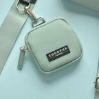 Pochette vert sauge avec mousqueton sur fond turquoise