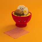 Bol de ramen posé sur fond orange avec une serviette à carreaux
