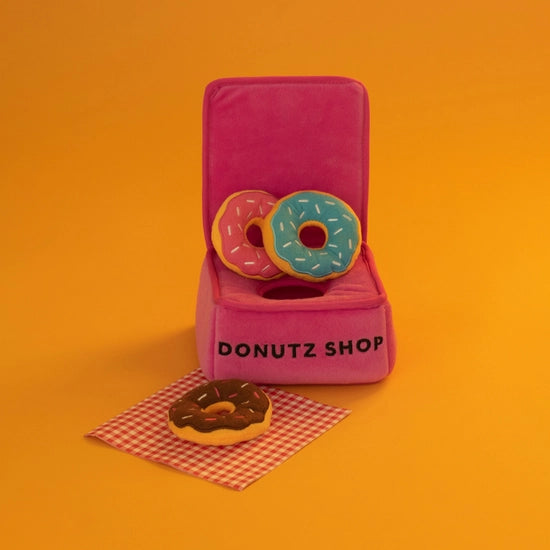 Boîte à donuts posée sur fond orange avec une nappe à carreaux