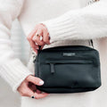 Mains tenant le sac noir rectangulaire à zip