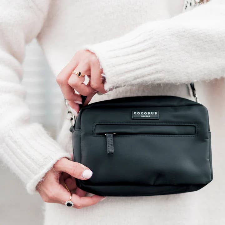 Mains tenant le sac noir rectangulaire à zip