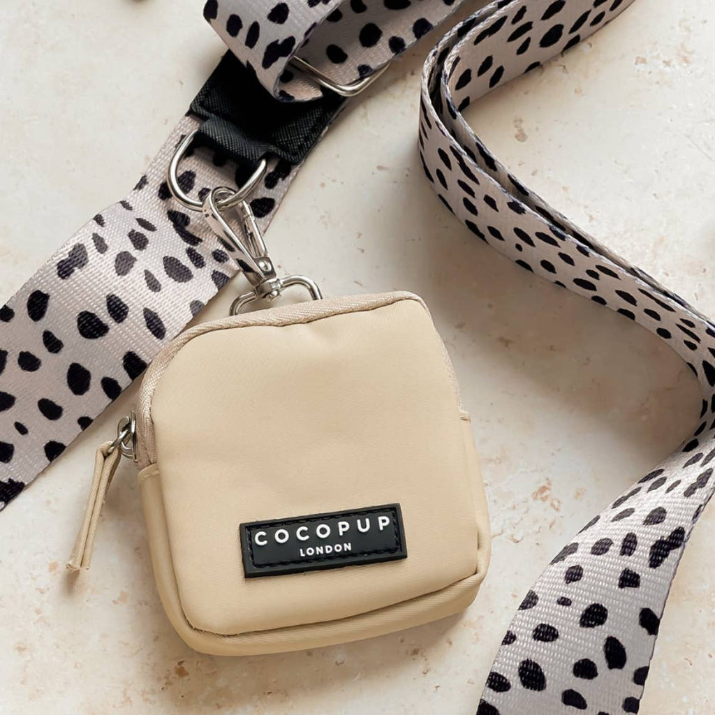 Pochette beige posée sur une sangle à pois noirs