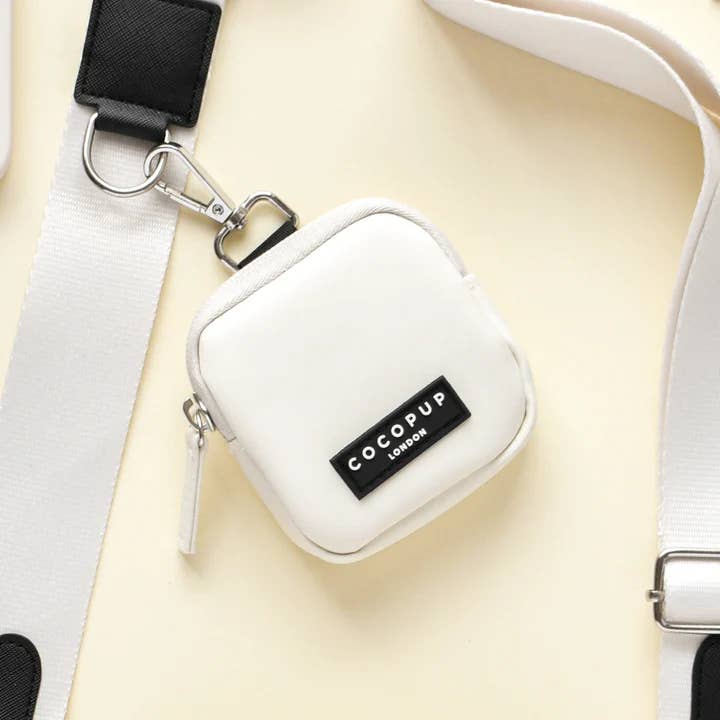 Pochette blanche à mousqueton noir sur fond crème