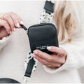 Mains ouvrant la pochette noire à fermeture éclair